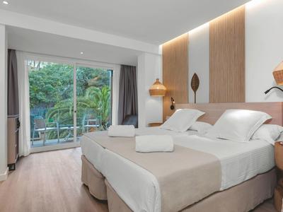 Chambre d'hôtel moderne avec deux lits, vue sur balcon et arbres verts