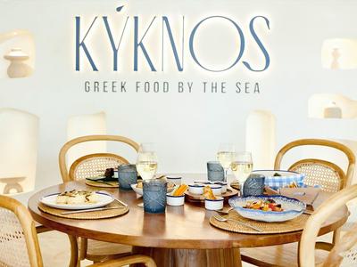 Tavolo elegante con cibo greco in un ambiente moderno e luminoso.