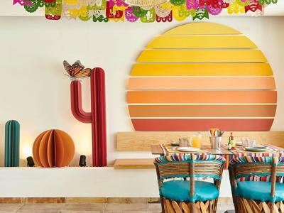 Interno di ristorante allegro con sedie colorate e decorazione murale solare.