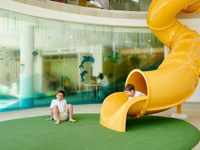 Bambini che giocano su uno scivolo giallo in un'area interna dell'hotel.