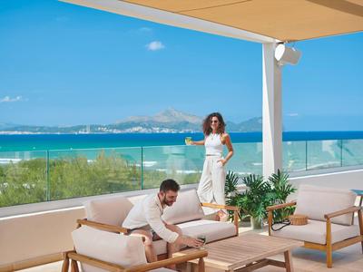 Terrasse mit Sitzbereich und Blick auf das Meer, entspannte Urlaubsstimmung bei Sonnenschein