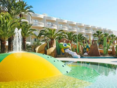 Piscine d'hôtel avec toboggans aquatiques et palmiers, entourée d'un bâtiment hôtelier blanc à plusieurs étages.
