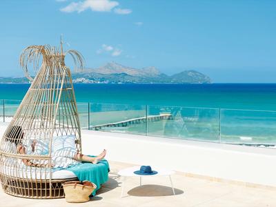 Cabina lounge moderna con sedia in vimini su terrazza soleggiata con vista mare.