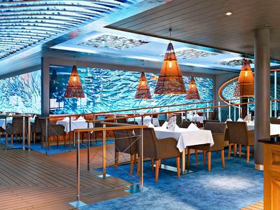 Modernes Restaurant mit großen Aquarienwänden, weißen Tischdecken und gemütlicher Atmosphäre.