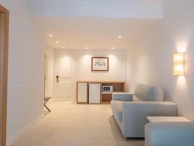 Heller Hotelzimmer mit Sofa, Minibar und moderner Beleuchtung.