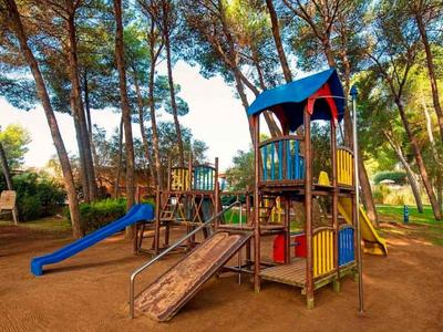 Bunter Spielplatz mit Rutschen und Klettergerüsten umgeben von Bäumen.