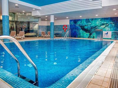 Innen-Schwimmbad mit blauer Fliesenwand und Treppe im Vordergrund