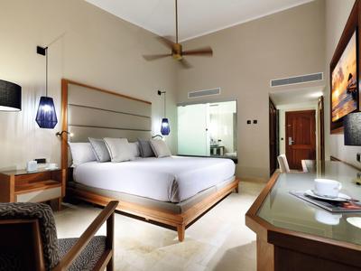 Modernes Schlafzimmer mit Holzmöbeln, weißem Bett und gedämpfter Beleuchtung.