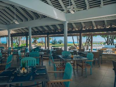 Otevřená restaurace s výhledem na moře a několika prostřenými stoly pod střechou.