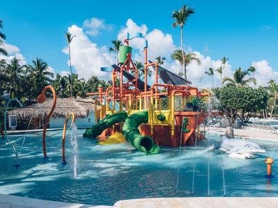 Area giochi acquatica colorata con scivoli in un ambiente tropicale della piscina dell'hotel con cielo soleggiato.