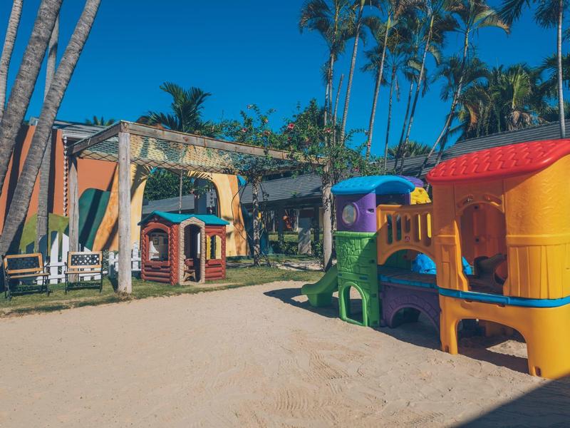 Area giochi colorata nella sabbia sotto le palme in un villaggio vacanze