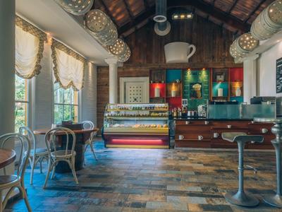 Café chaleureux avec intérieur rustique, sol en bois et grandes fenêtres.