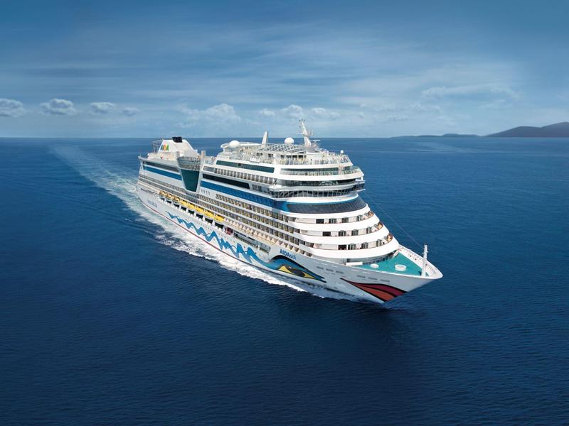 Grand navire de croisière naviguant sur une mer calme sous un ciel nuageux.