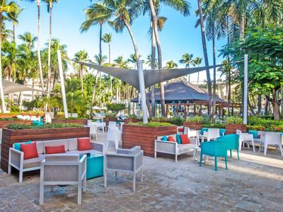 Outdoor area of a tropical hotel with seating and palm trees under a blue sky.