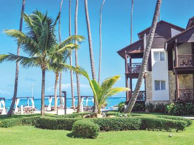 Hotel with tropical garden, palm trees, and ocean view at the beach.