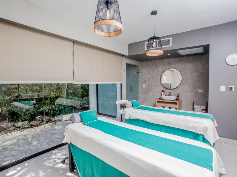 Massage room with two beds, large windows, and garden view