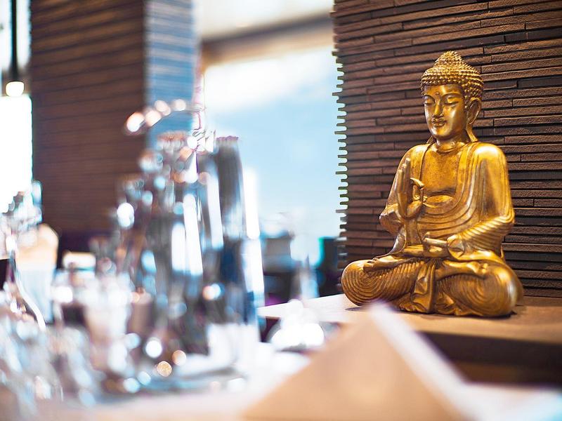 A golden Buddha statue beside a set dining table in a restaurant.