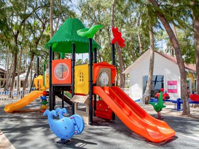 Bunter Kinderspielplatz mit Rutschen und Schaukeln in einem bewaldeten Hotelgarten.