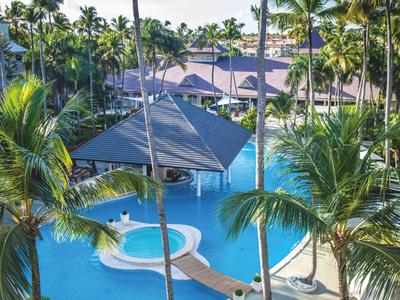 Área de piscina con palmeras y una sección cubierta en un resort tropical