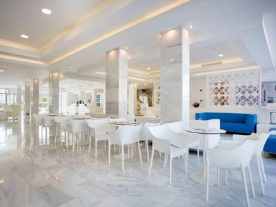 Bright, modern dining area with white chairs, tables, and blue sofas.
