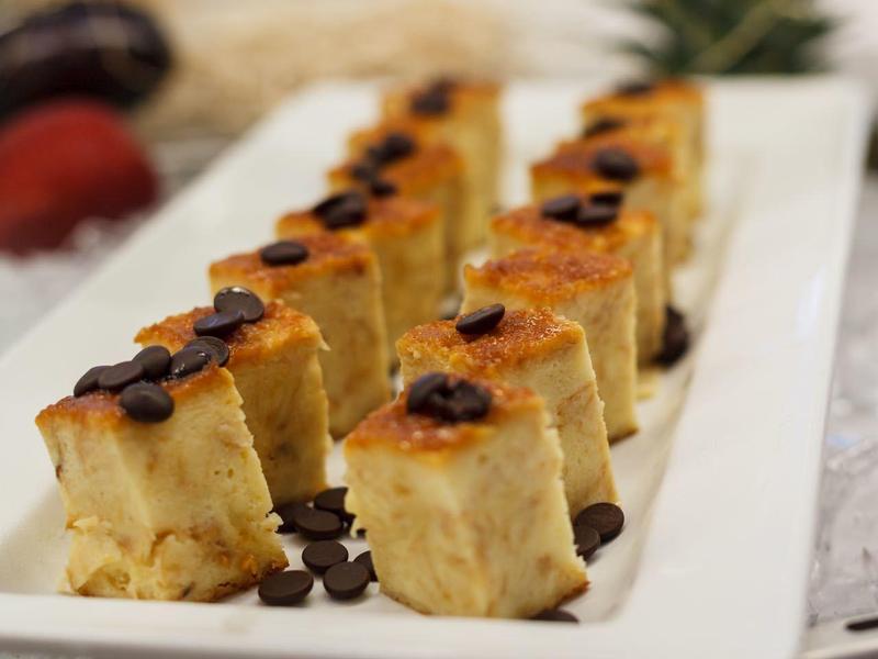 Row of delicious sushi pieces on a white rectangular plate.
