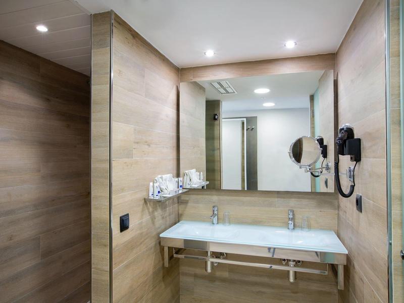 Hotel bathroom with wooden walls, double sink, large mirror, and modern lighting.