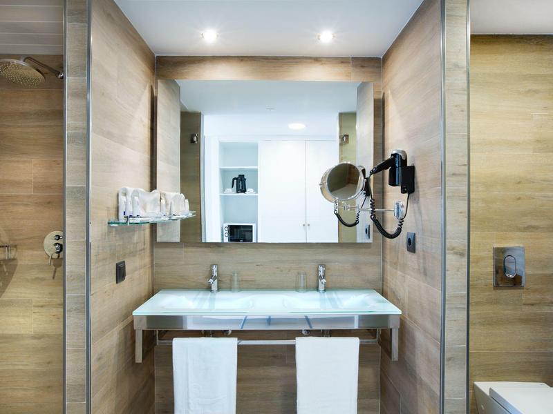 Baño moderno con lavabo doble, espejos grandes y paneles de madera.