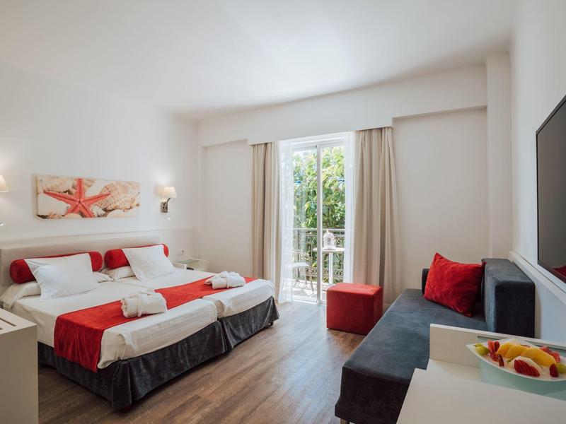 Chambre d'hôtel moderne avec lit double, balcon et coin salon confortable avec canapé.