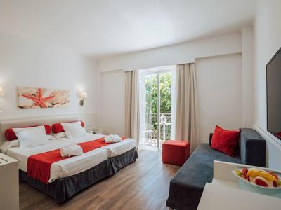 Camera d'hotel moderna con letto matrimoniale, balcone e confortevole zona salotto con divano.