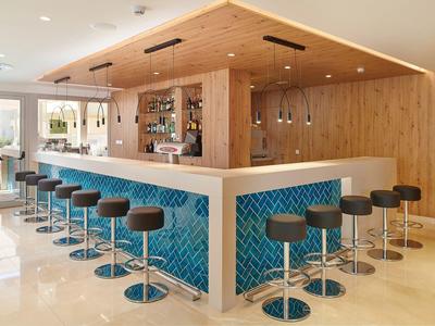 Bar moderne avec tabourets, murs en bois et carrelage bleu, ambiance lumineuse et épurée.