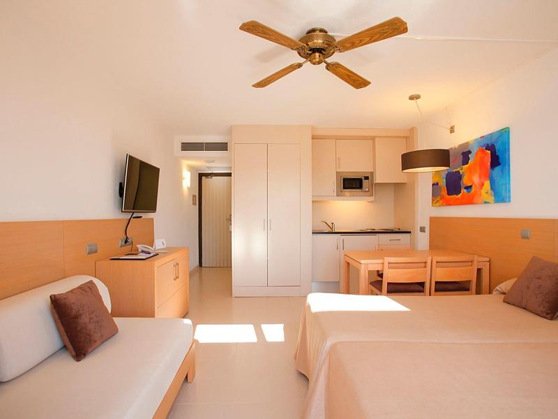 Chambre d'hôtel spacieuse avec lit, canapé, petite cuisine et décoration moderne.