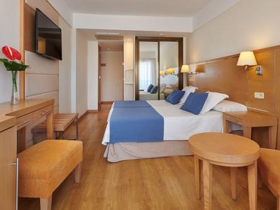 Camera d'hotel luminosa con letto matrimoniale, mobili in legno e biancheria da letto blu.