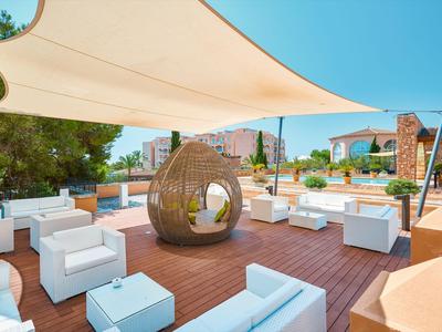 Área exterior moderna con elegantes muebles blancos y un columpio colgante de mimbre en terraza de madera.