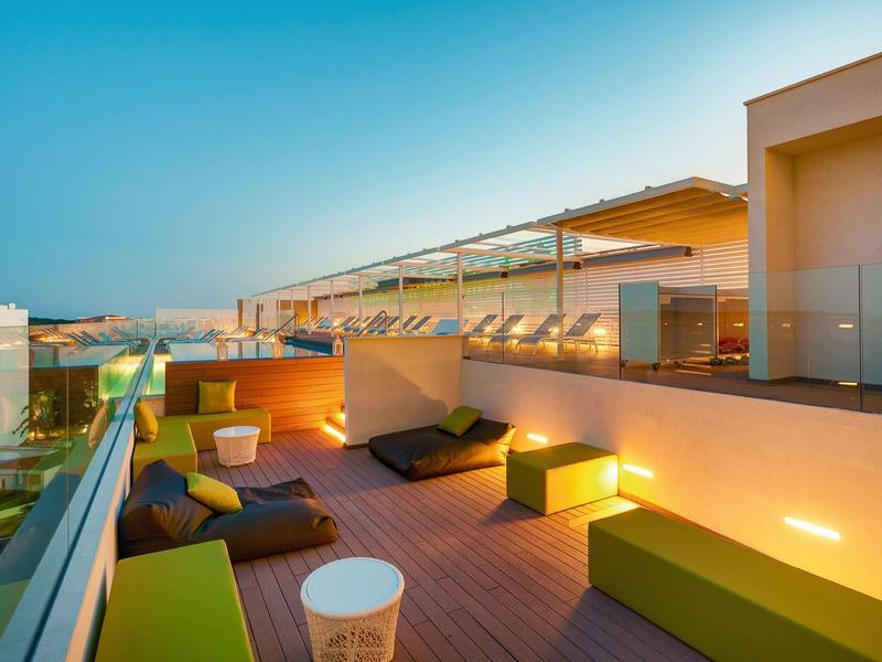 Modern rooftop terrace with seating and lighting at sunset.