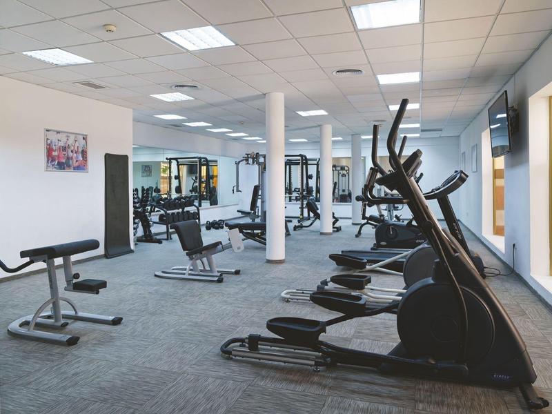 Modern gym room with various exercise machines and large windows