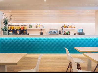 Moderní hotelový bar s modře osvětleným barem a dřevěnými židlemi.