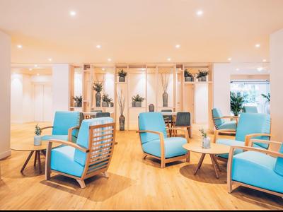 Jasny salon z wygodnymi niebieskimi fotelami i drewnianą podłogą w hotelu.