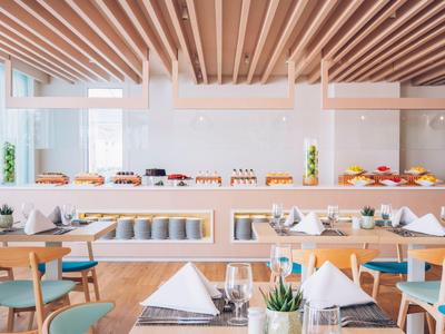 Nowoczesna restauracja z elegancko nakrytymi stołami i ciepłym drewnianym wystrojem.