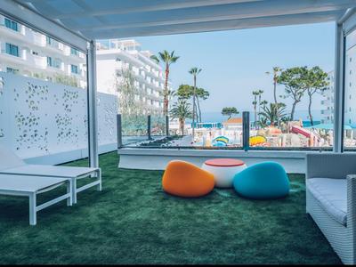 Modern lounge area with bean bags overlooking pool and palm trees.