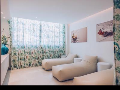 Modern room with light furniture and patterned curtains on large windows.