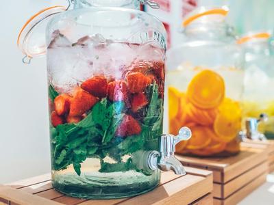 Caraffa di vetro con ghiaccio, menta e fragole tagliate, ideale per le vacanze estive.