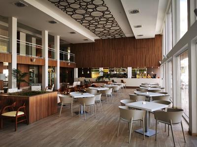 Moderne hotelrestaurant met witte stoelen, houten wanden en grote ramen.