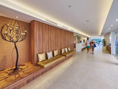 Area hall di hotel moderna con panche in legno e opera d'arte ad albero decorativa sulla parete.