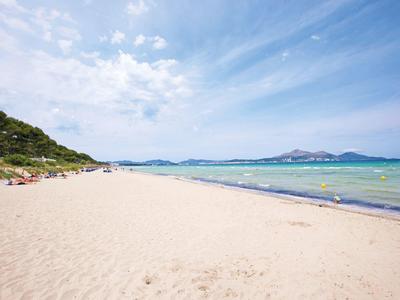 Large plage de sable avec eau claire et ciel bleu dans une destination de vacances.