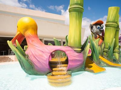 Bunte Wasserrutsche mit Oktopus-Design und Treppe, umgeben von Wasser im Außenbereich.