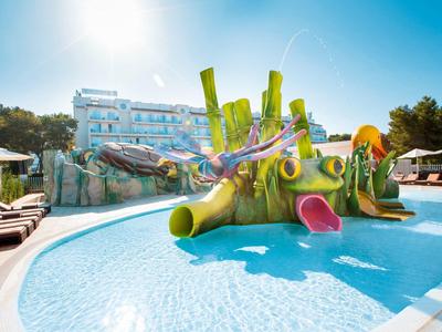 Aire de jeux aquatique colorée avec toboggans dans une piscine devant un hôtel par temps ensoleillé.