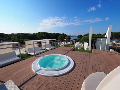 Moderner Whirlpool auf einer Dachterrasse mit Sitzgelegenheiten und Blick aufs Meer.