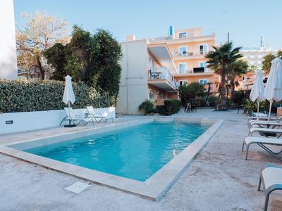 Piscine extérieure moderne avec chaises longues et parasols devant un hôtel par une journée ensoleillée.