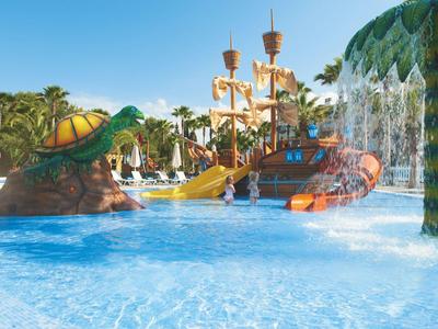 Colorful water playground with pirate ship and turtle in a bright hotel pool.