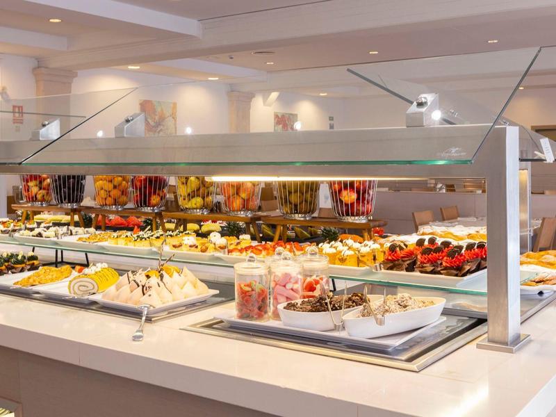 Buffet with various desserts, cakes, and fruits in a restaurant.